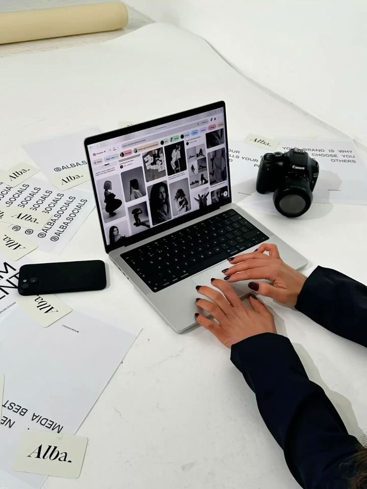 Creative workspace with a laptop, camera, and brand print layouts